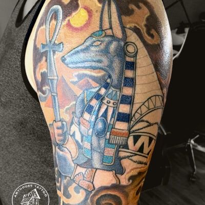 Anubis-inspired tattoo on person's arm.